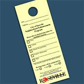 A yellow door hanger from the Neighborhood Enhancement Program